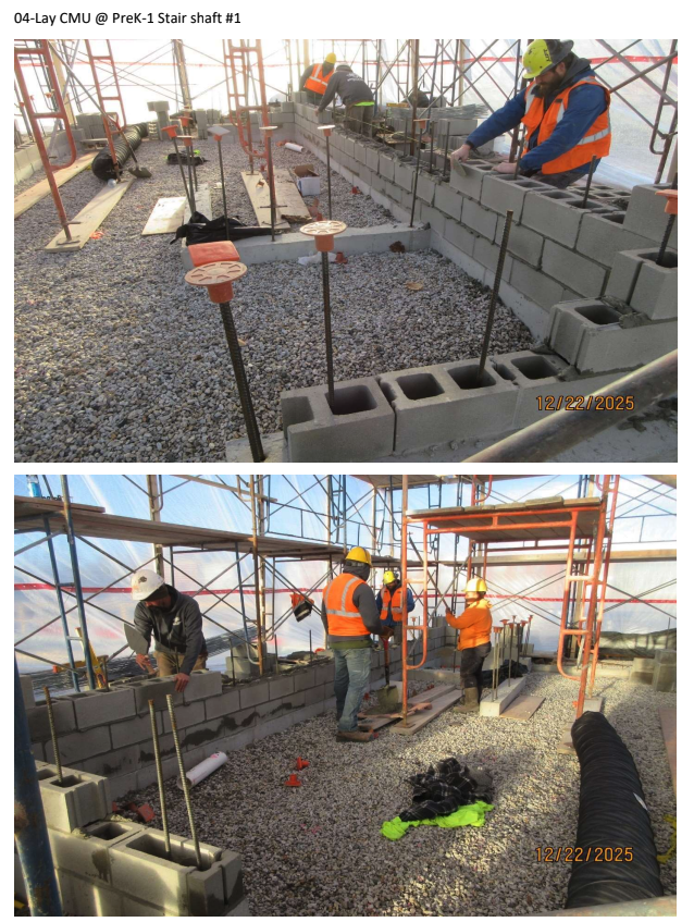 Workers laying concrete masonry units at a stair shaft construction site.
